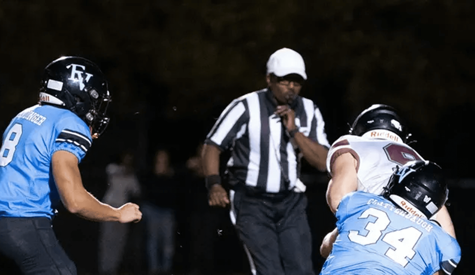 Football game action with referee observing play.