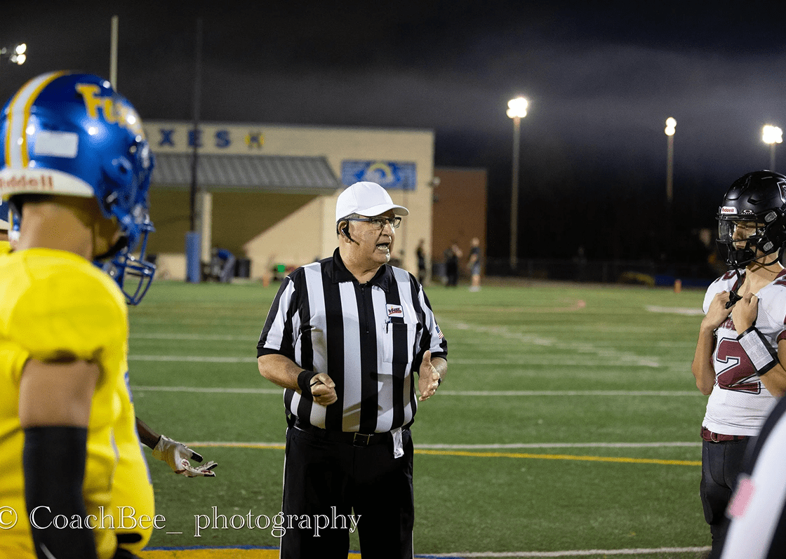 Football referee at midfield with players.