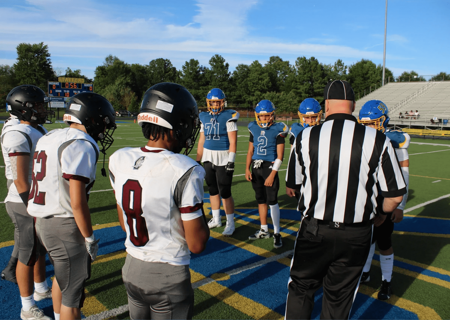 Football players during coin toss on field.