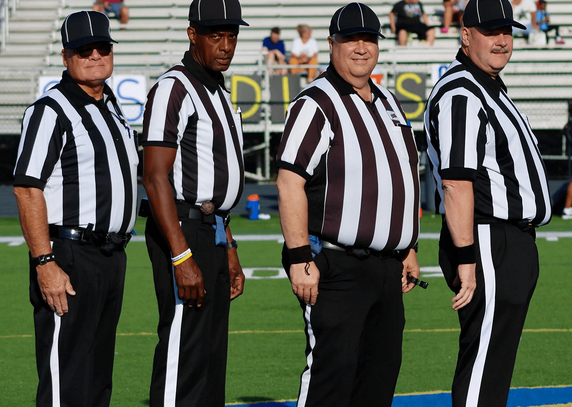 Four referees standing on a sports field.