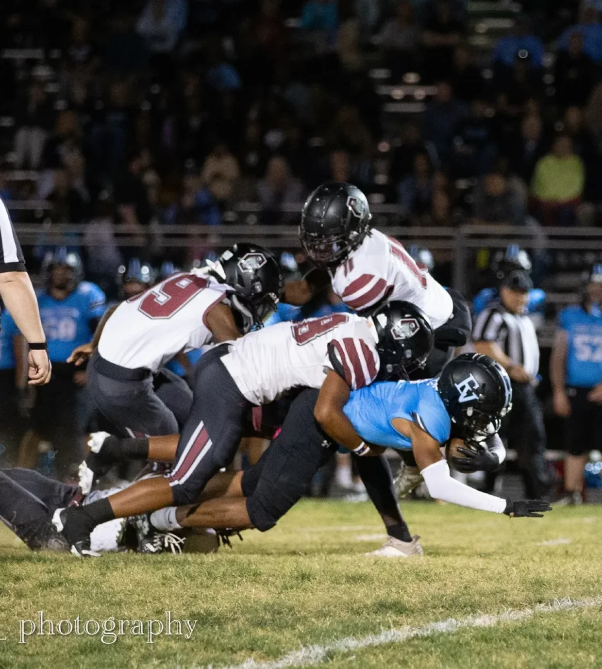 Football players tackling during a night game.