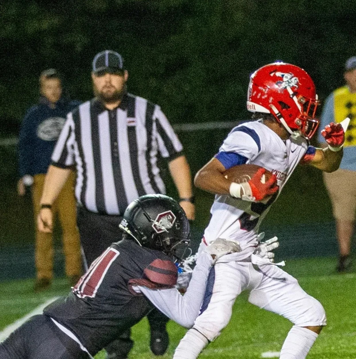 Football player tackled during night game.