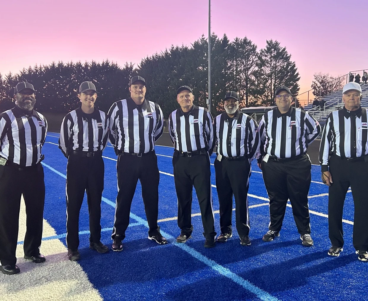 Group of referees standing on blue field.