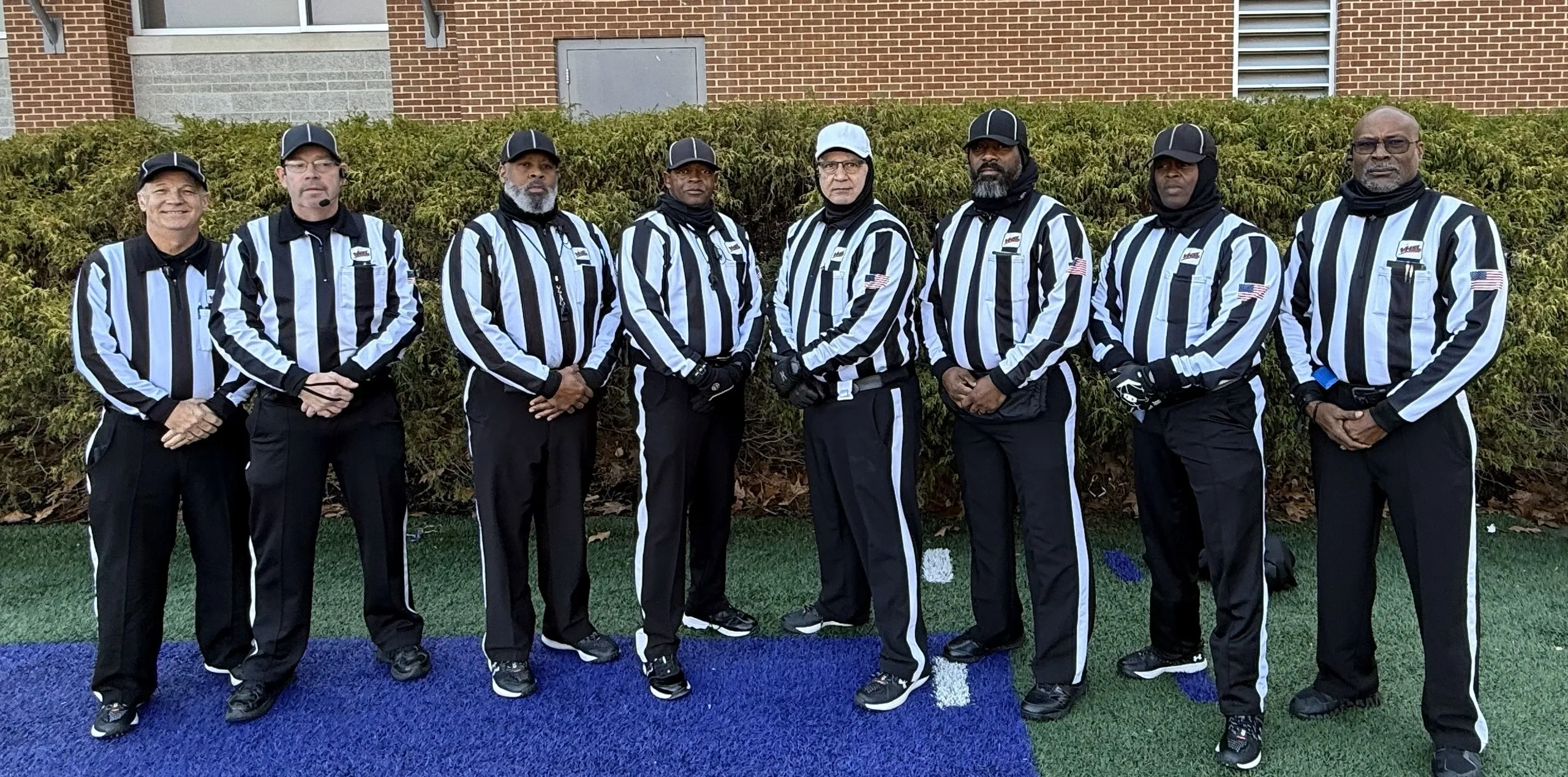 Group of football referees in striped uniforms.