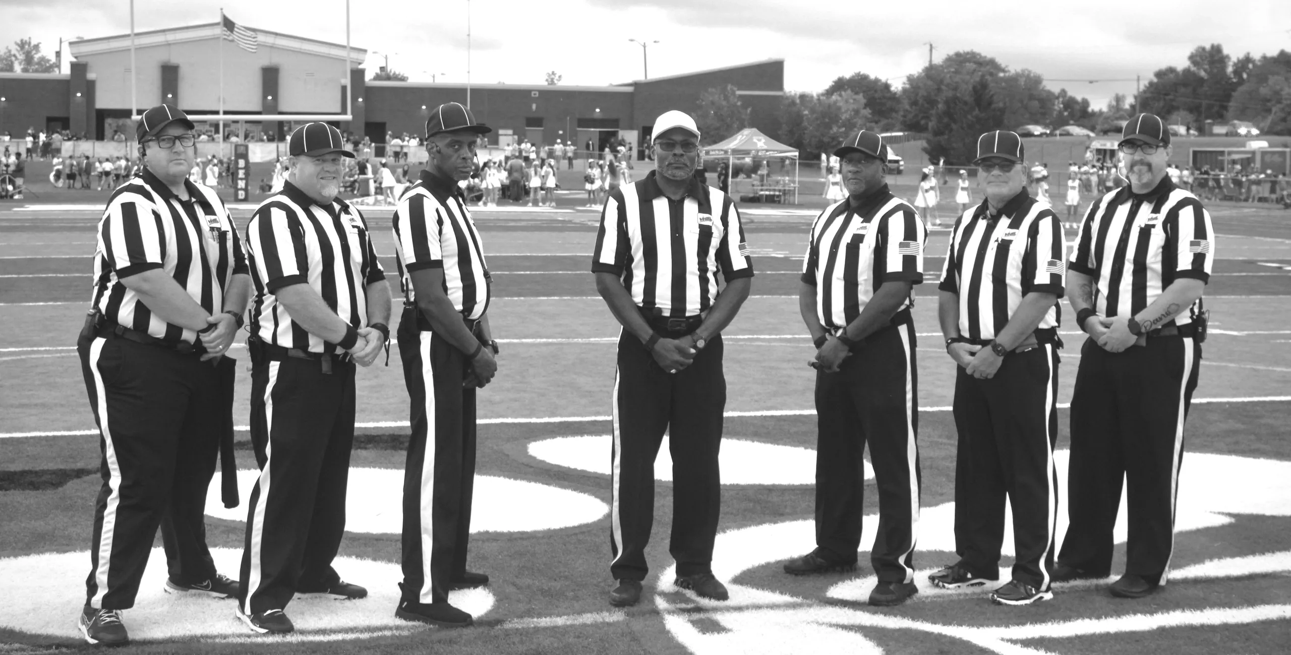 Group of referees standing on football field.