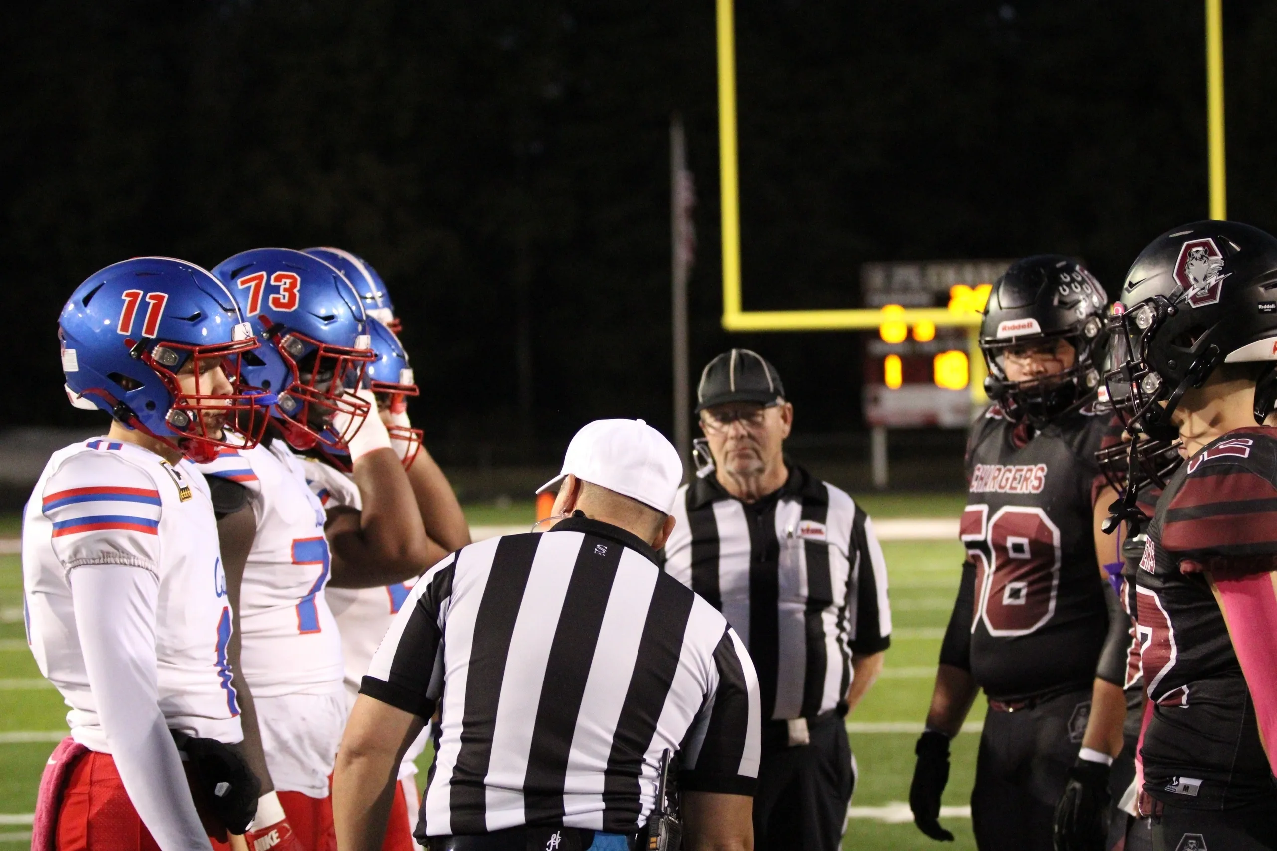 Football players at midfield for coin toss.
