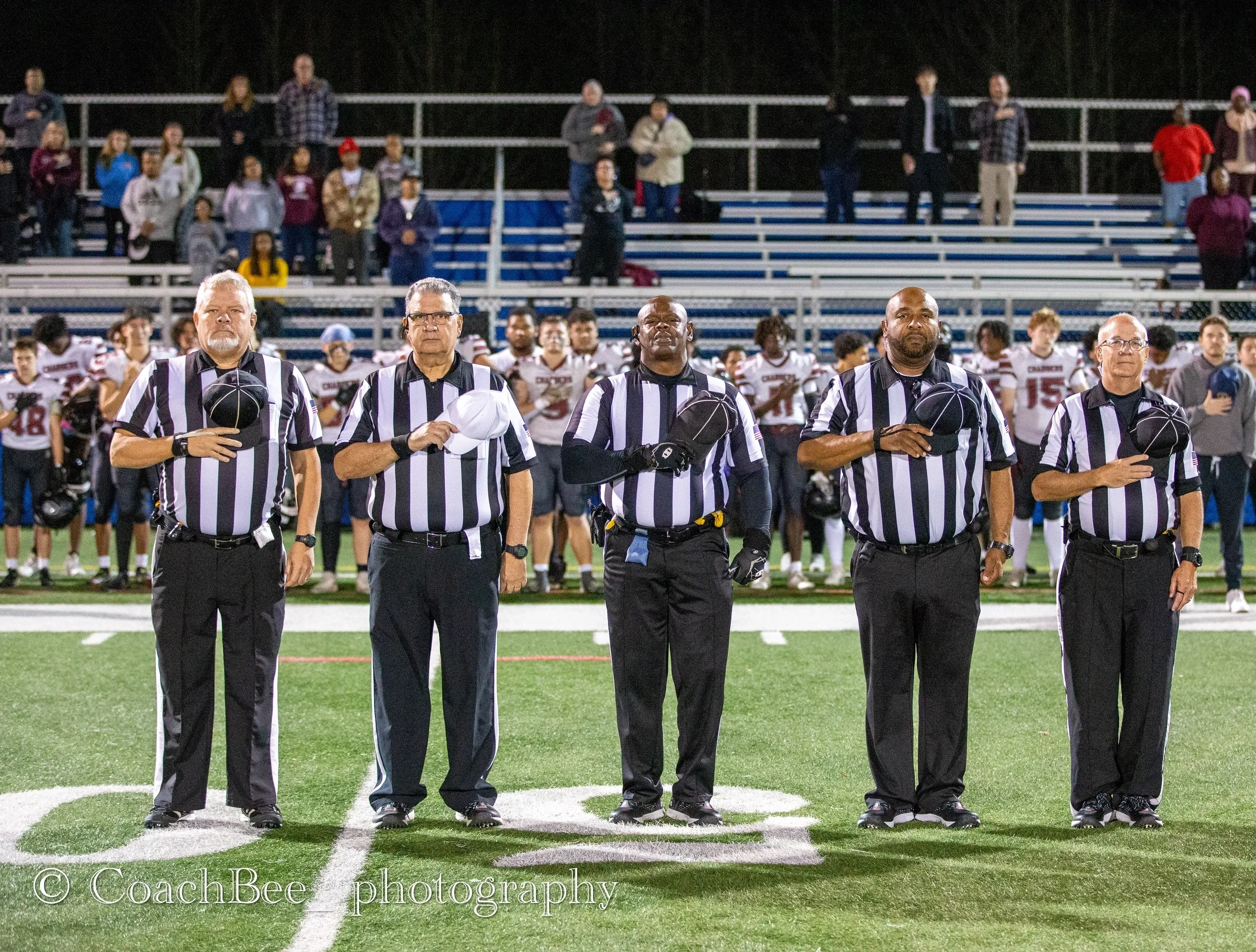 Football referees standing for national anthem.
