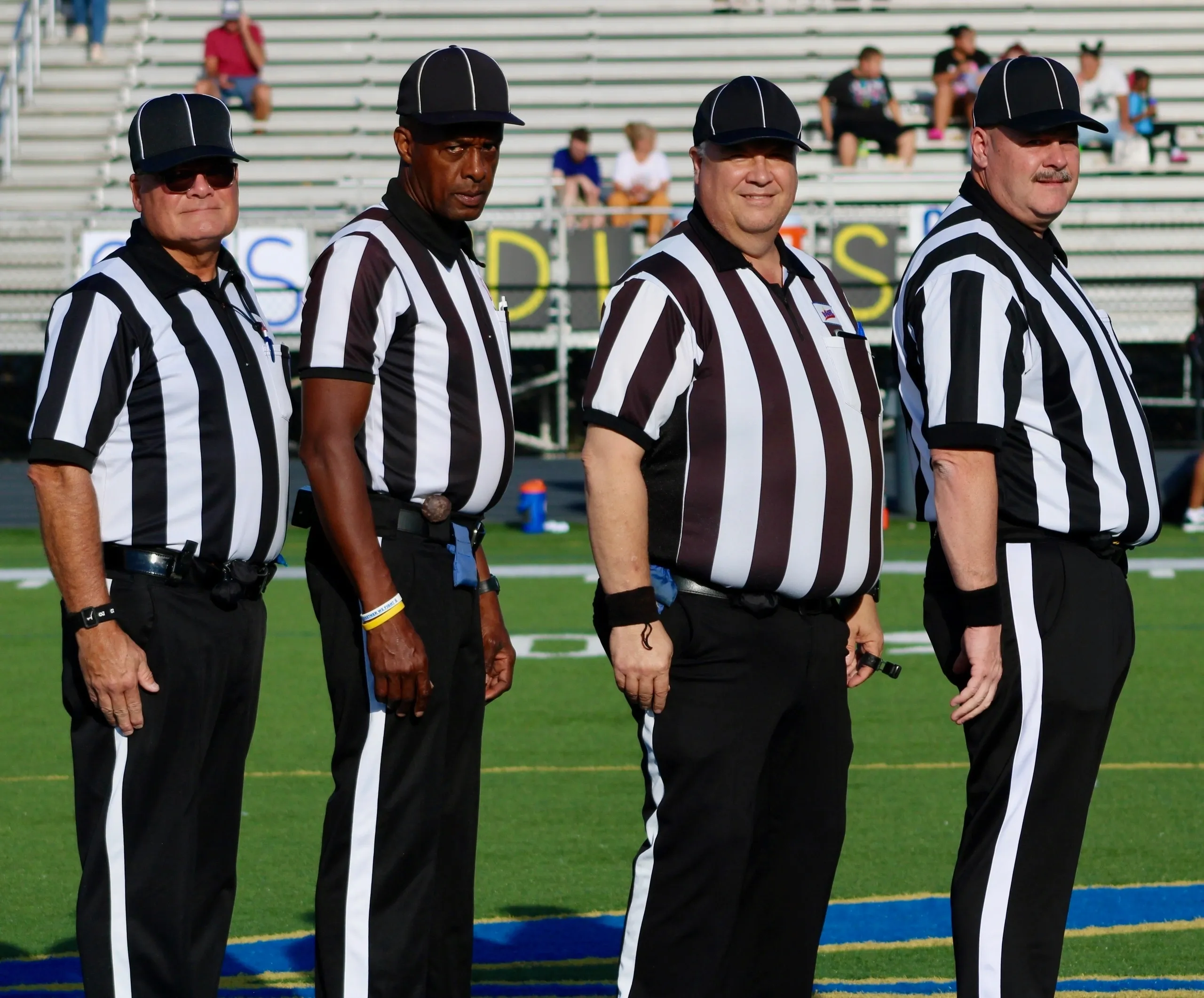 Four referees standing on a football field.